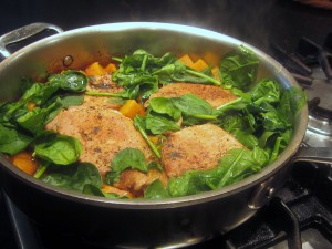 Pork in skillet with baby spinach